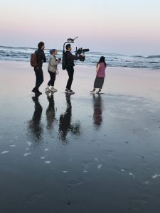 people filming on a beach